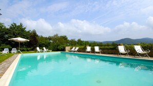 Una piscina con sillones blancos y una pared de piedra.