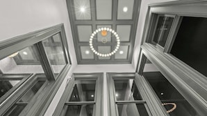 A high-ceilinged room with multiple windows and a central light fixture.