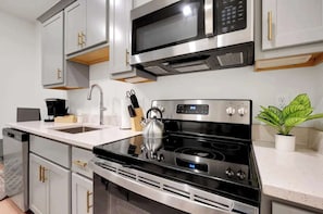 A modern kitchen with stainless steel appliances, white cabinetry, and a kettle on the stove.