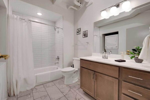 Et moderne badeværelse med badekar, toilet, vaskebord med spejl og brusenik.