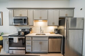 Una cocina moderna con electrodomésticos de acero inoxidable, armarios de color gris claro y lavavajillas integrado.