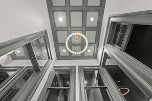 Ein mehrgeschossiges Interieur mit einem zentralen Oberlicht, zahlreichen Fenstern und einer runden Leuchte.