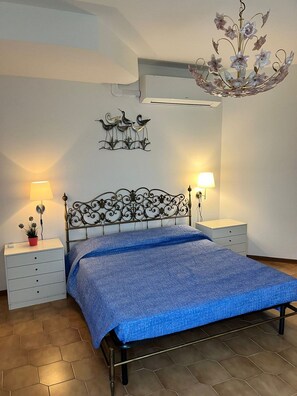 A bedroom with a bed, two bedside tables, a wall-mounted light fixture, and a wall decoration. - Terrazza sul Mare (Marina Julia)