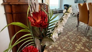 Un salon comprenant un canapé, une table à manger avec des chaises, un vase décoratif avec des fleurs et un sol à motifs.
