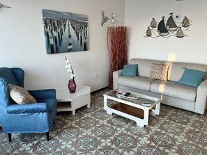 A living room with a sofa, armchair, coffee table, and decorative items. - Terrazza sul Mare (Marina Julia)