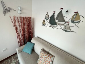 A living room with a sofa, decorative wall art, and a patterned throw pillow. - Terrazza sul Mare (Marina Julia)