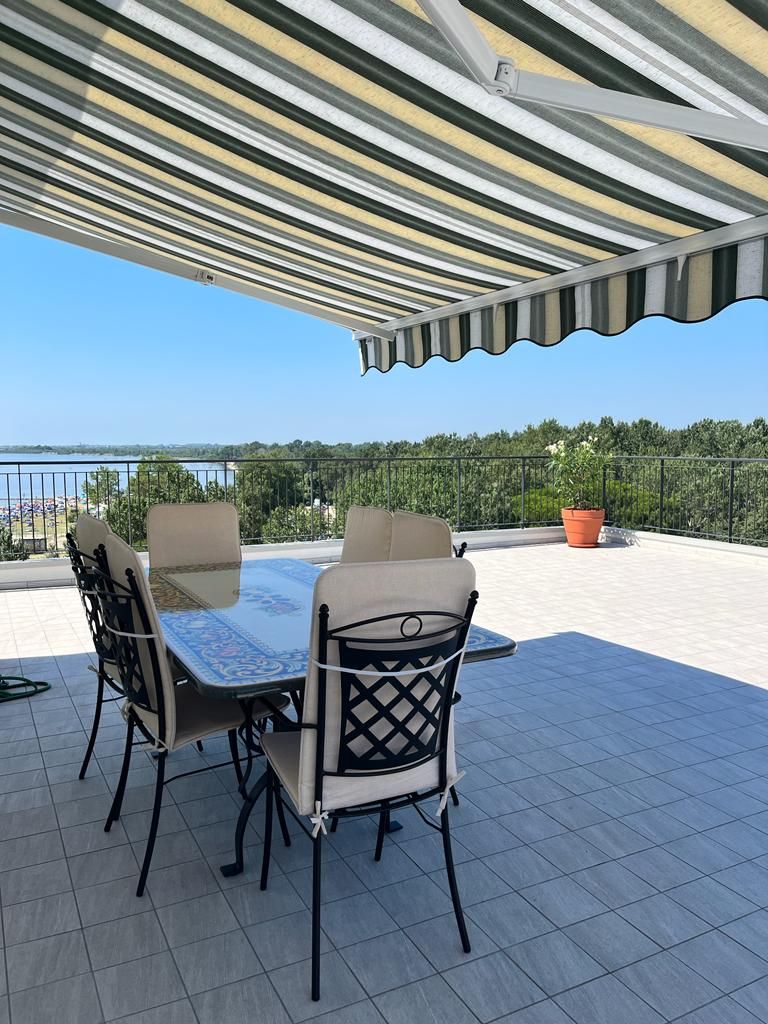Eine Außenpatio mit Tisch und Stühlen, einem überdachten Bereich und Blick aufs Meer.