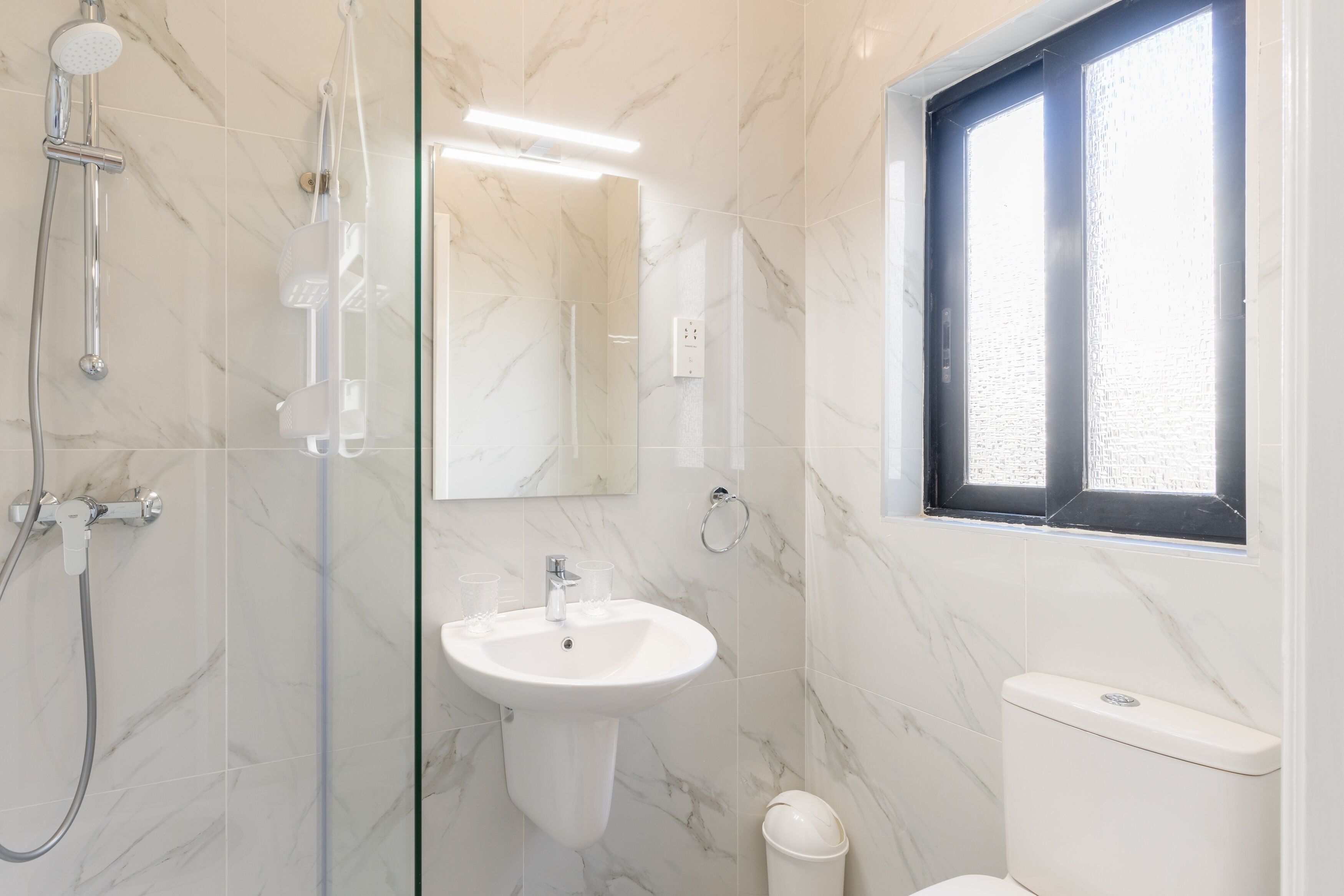 Une salle de bain avec une douche à parois de verre, un lavabo et des toilettes.