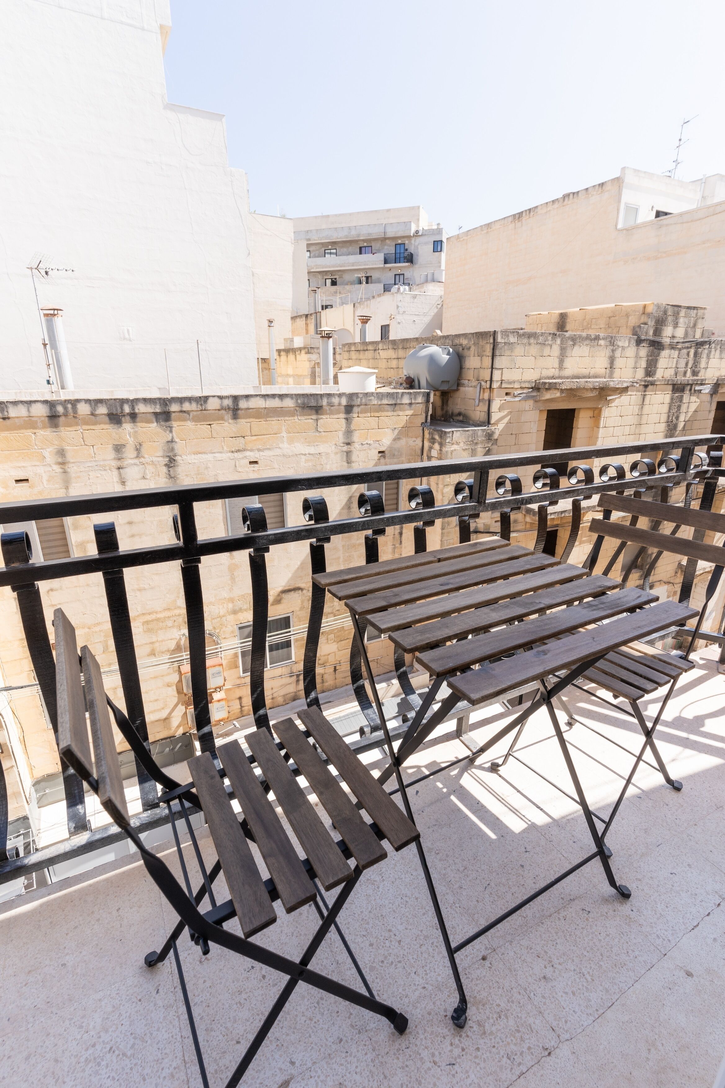 Un balcó amb barana metàl·lica i bancs de fusta.
