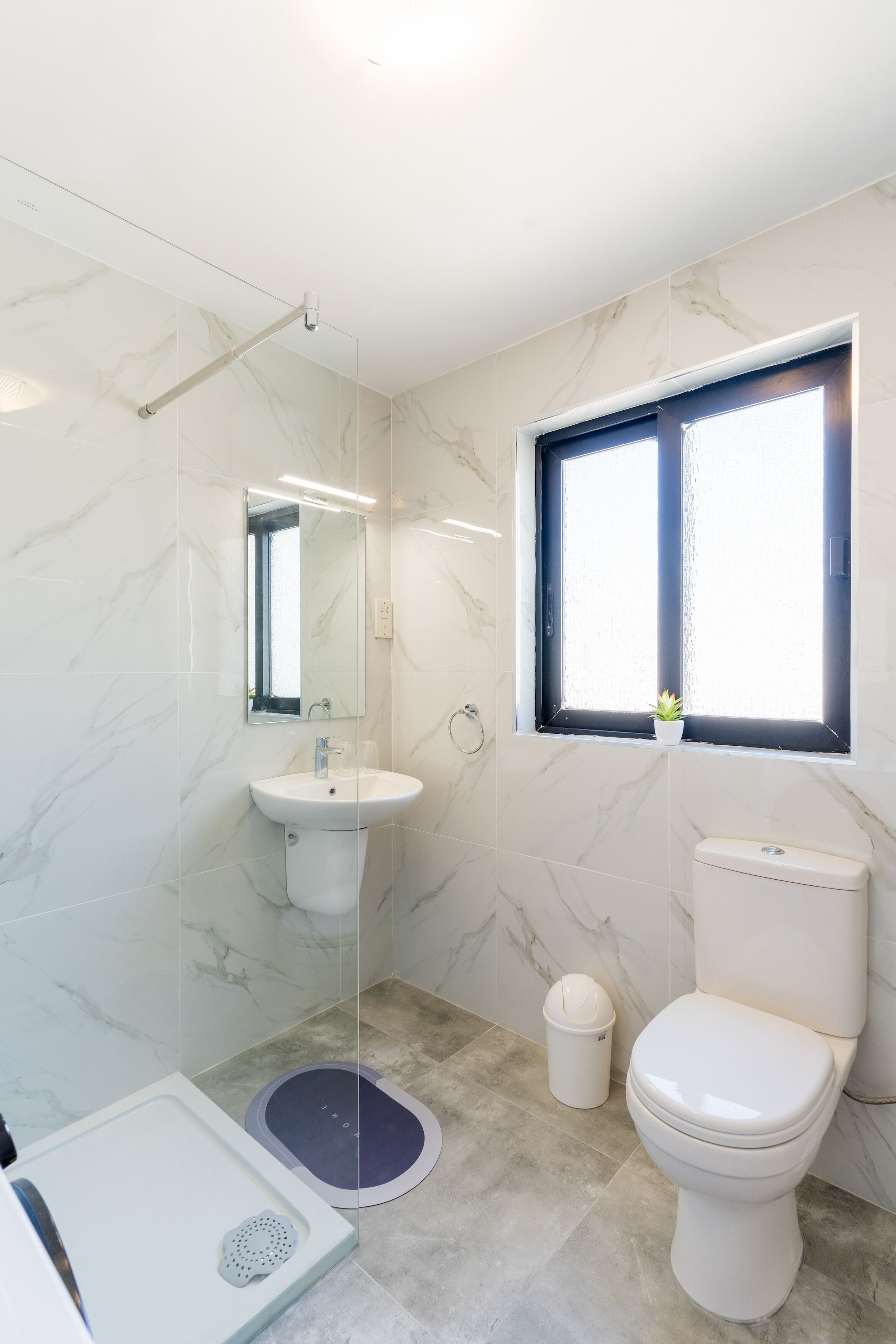 A modern bathroom with a toilet, sink, and shower.