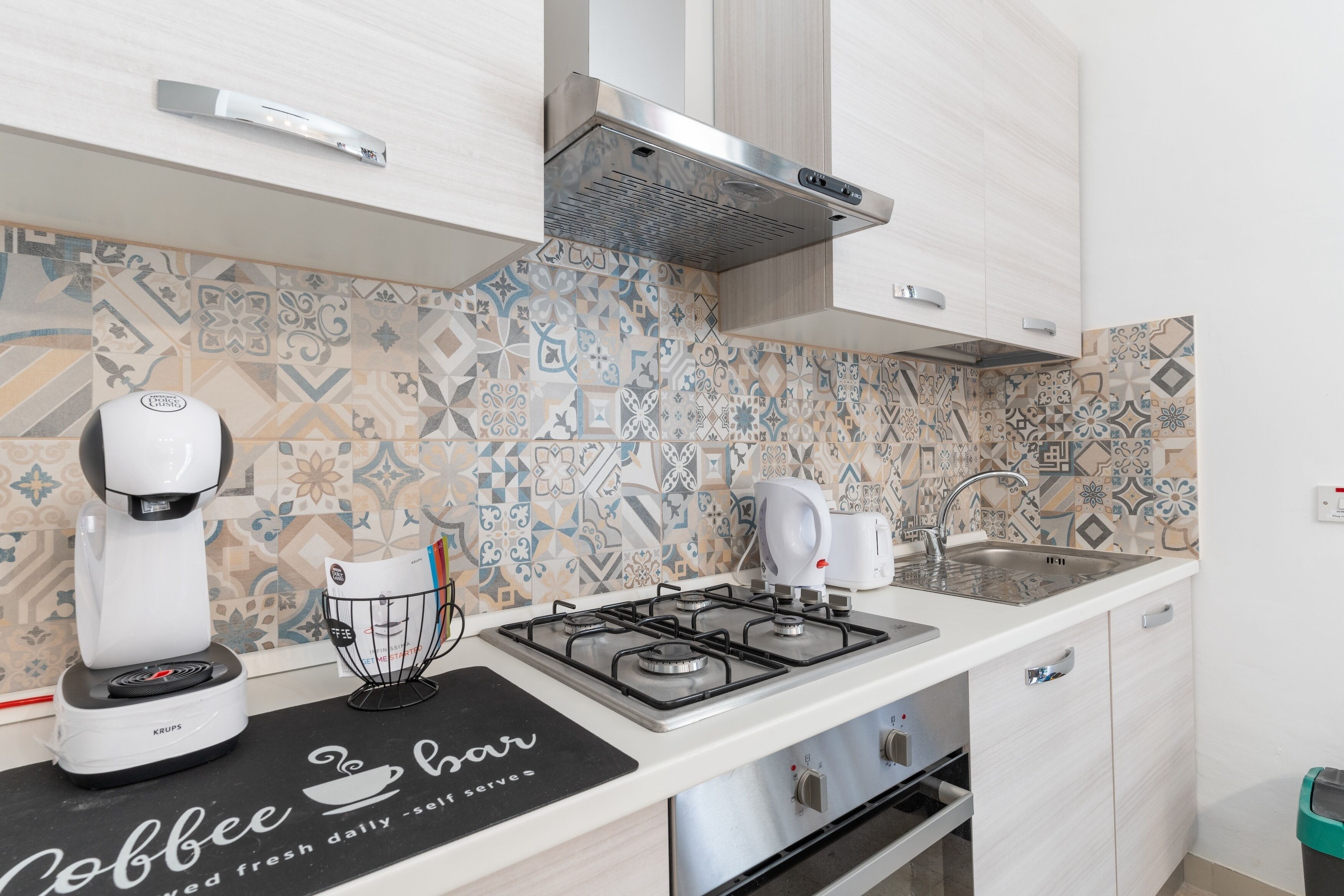 A modern kitchen with a coffee machine, a kettle, and a gas stove.
