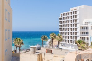 A coastal hotel with a view of the sea, palm trees, and a modern building with balconies. - Tempo Suites (St. Paul's Bay)