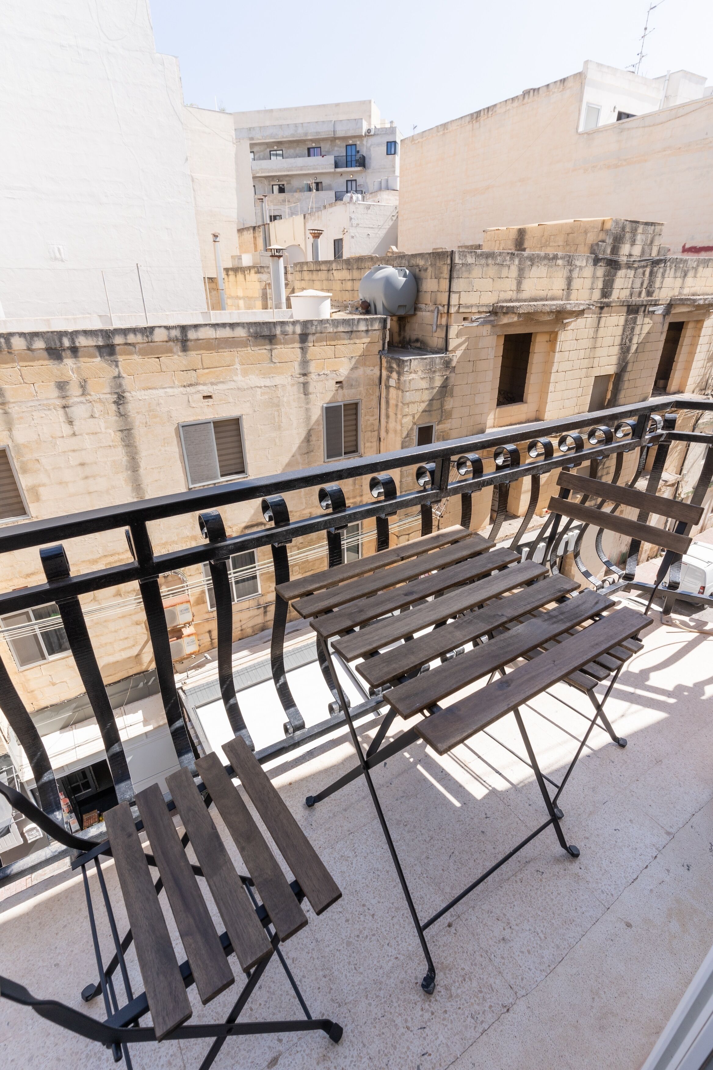 A balcony with a wooden bench and a metal railing.