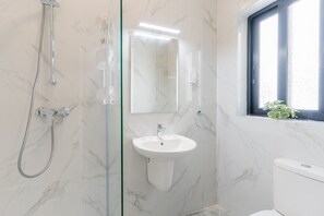 A bathroom with a glass-enclosed shower, a white sink, and a toilet. - Tempo Suites (St. Paul's Bay)