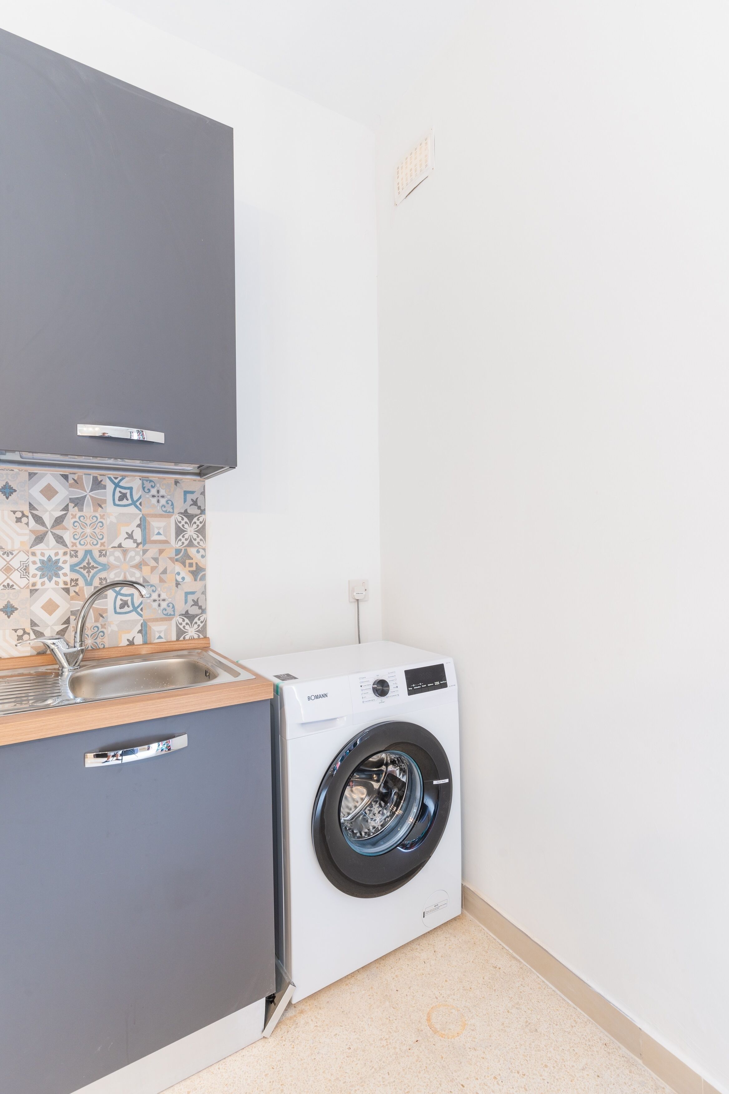 Eine kleine Küche mit Waschmaschine, Spüle und Schrank.