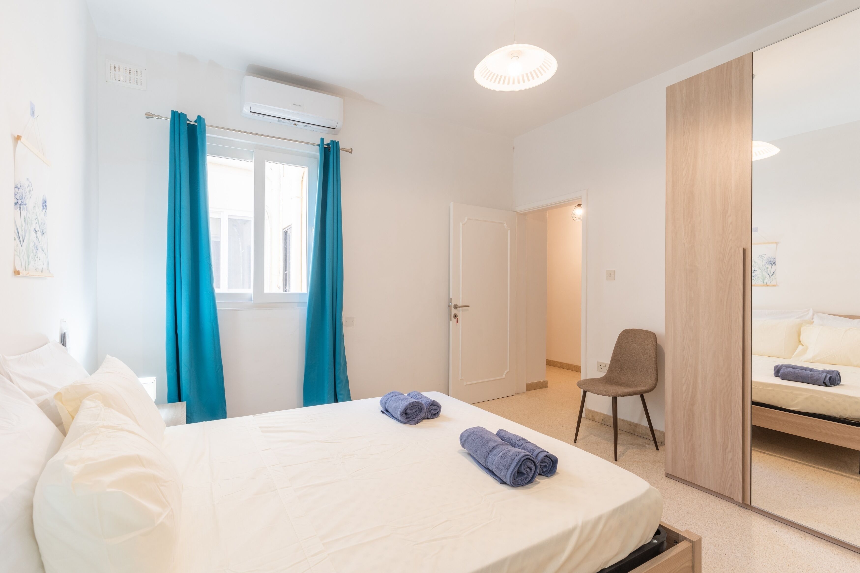 Une chambre d’hôtel comprenant un lit, une chaise, une armoire et une porte donnant sur une autre pièce.