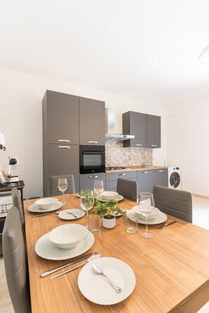 A modern kitchen with grey cabinets, a built-in oven, and a washing machine. - Tempo Suites (St. Paul's Bay)