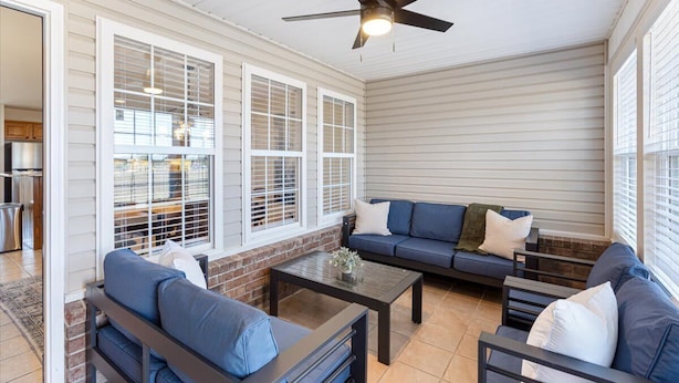 A covered patio with a ceiling fan, a sofa set, and a dining area.