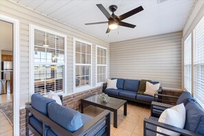 Un patio couvert avec un ventilateur de plafond, un ensemble de canapés et un coin repas.