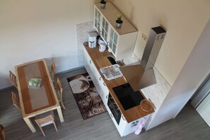 A compact kitchen with a dining area, a built-in oven, a coffee maker, and a small potted plant. - Modern Holiday Home in Brusow With Roofed Terrace (Kroepelin)