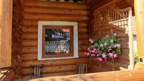 Eine Holzhütte mit Fenster, einer Holzbank und einem hängenden Blumenkorb.
