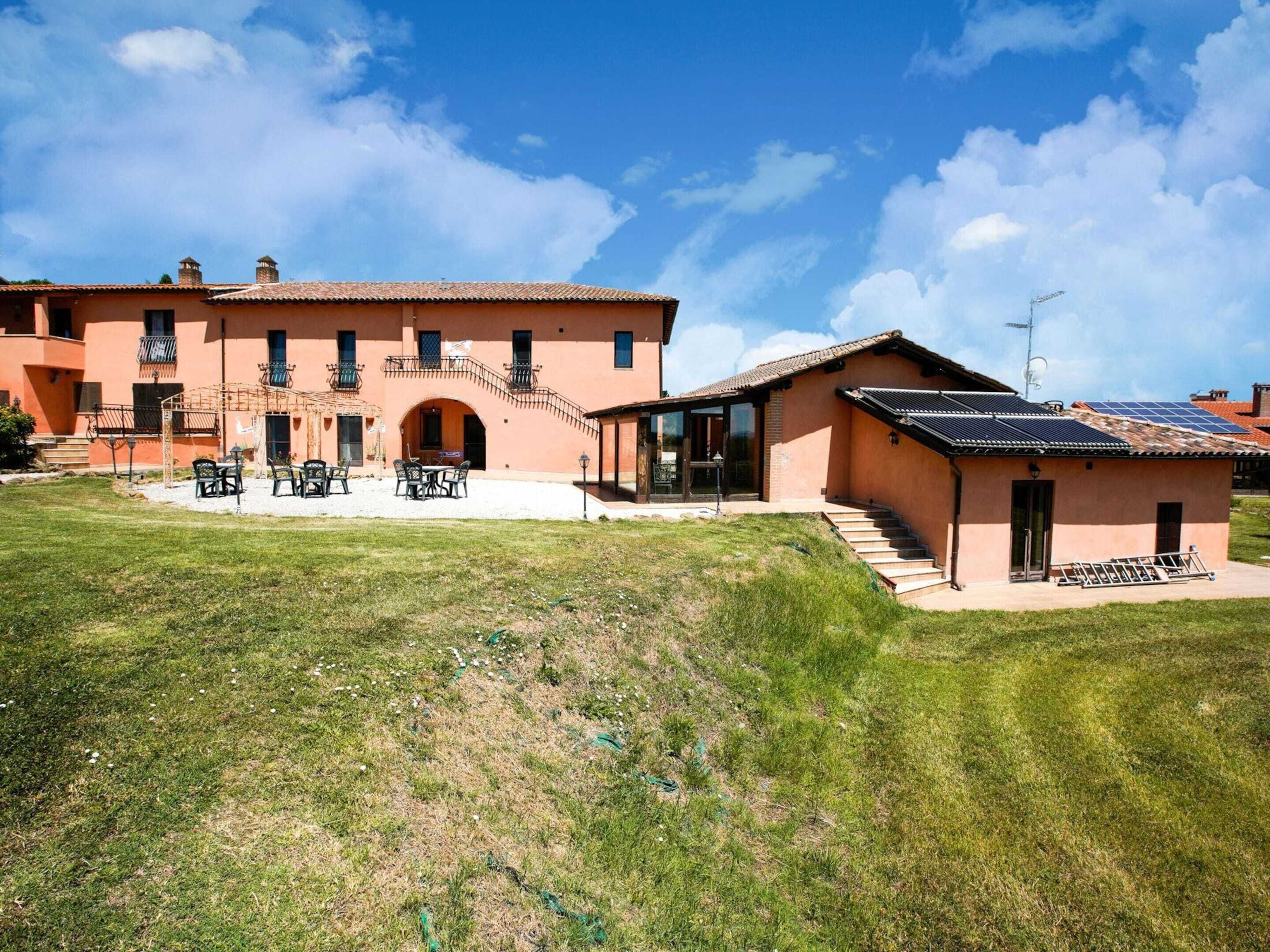 A two-story building with a patio area and a separate structure with solar panels.