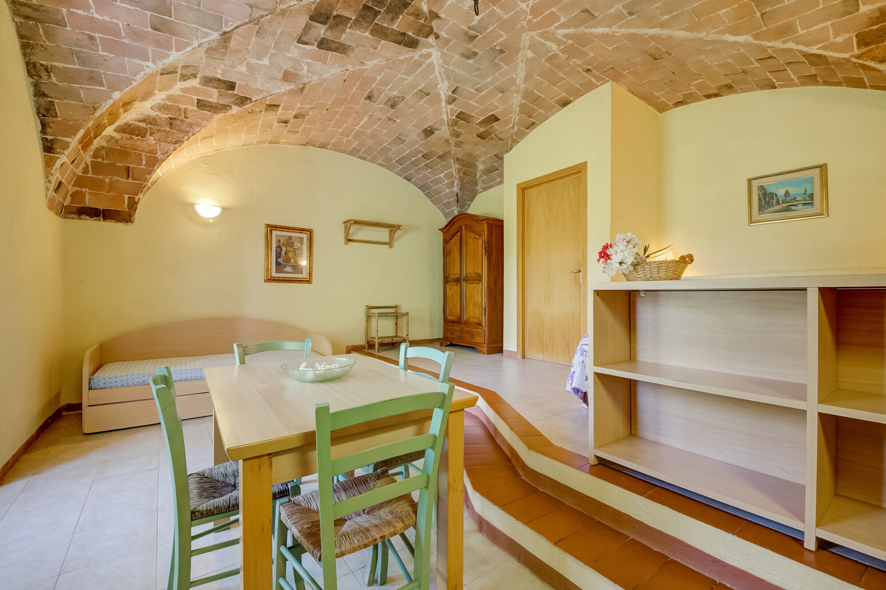 Um quarto acolhedor com uma mesa de jantar de madeira, cadeiras, um banco e uma lareira.