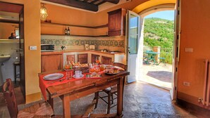 A kitchen with a dining table set for breakfast, a view of the outdoors, and a rustic interior design. - Picturesque Holiday Home in Assisi With Pool (Assisi)