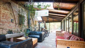 A rustic outdoor seating area with brick walls, wooden beams, and potted plants. - Holiday Home in Castiglione del With Pool (Castiglione del Lago)