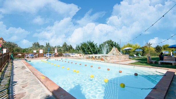A swimming pool with clear blue water, surrounded by lounge chairs and umbrellas. - Holiday Home in Castiglione del With Pool (Castiglione del Lago)