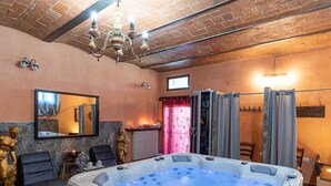 A spa room with a hot tub, a mirror, a statue, and a chandelier. - Holiday Home in Castiglione del With Pool (Castiglione del Lago)