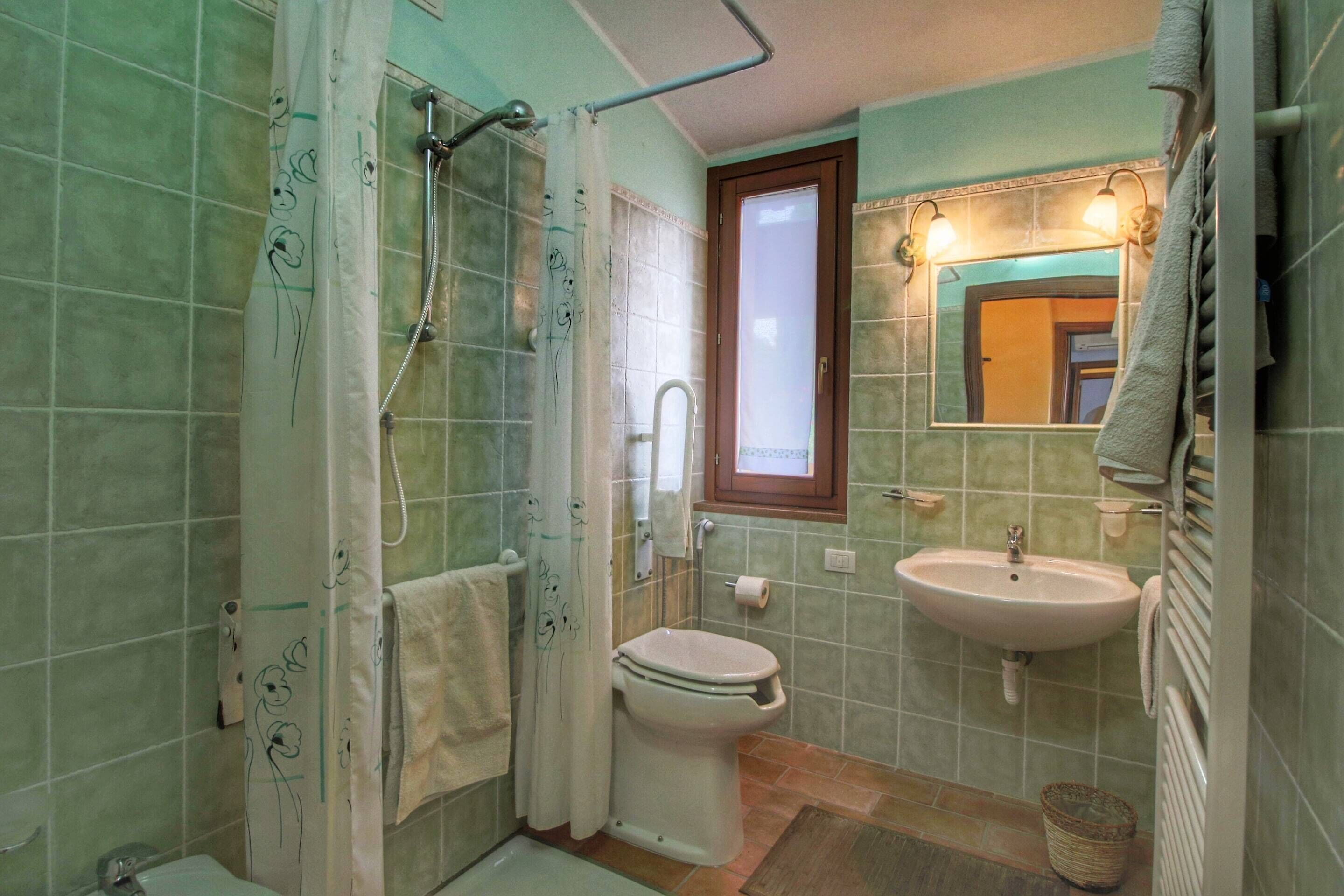 A bathroom with a shower, toilet, sink, and a window.
