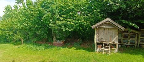 A wooden structure with a ladder, surrounded by lush green grass and trees.