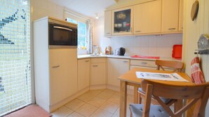 A compact kitchen with a refrigerator, oven, and a small dining table with chairs.