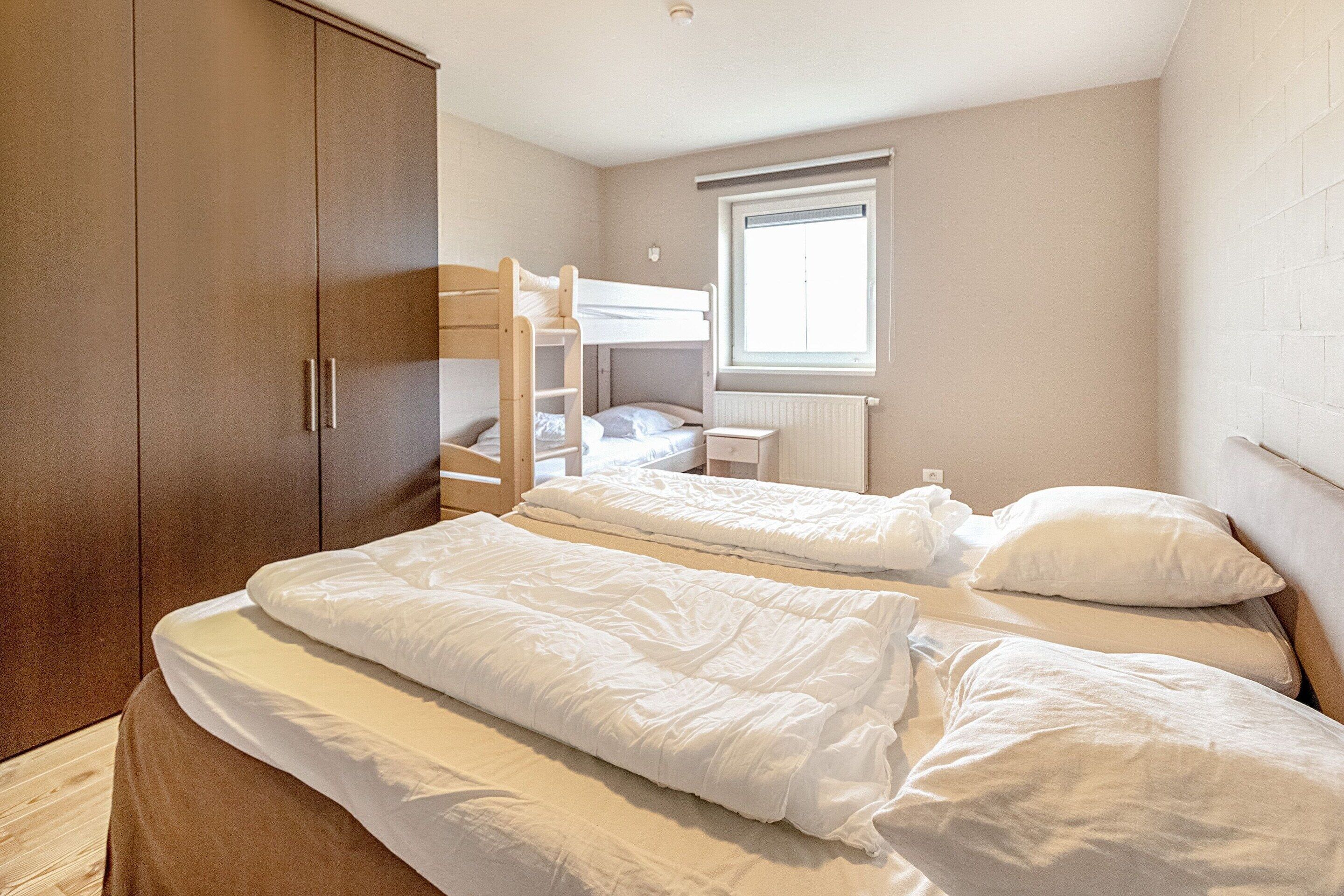 Ein Schlafzimmer mit zwei Etagenbetten, einem Holzschrank und einem Fenster mit Jalousien.