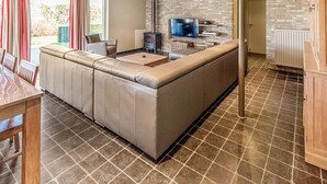 A modern kitchen with a large island, a built-in TV, and a stone wall backsplash. - Ideal Holiday Home in Gijverinkhove With Terrace, Garden (Alveringem)