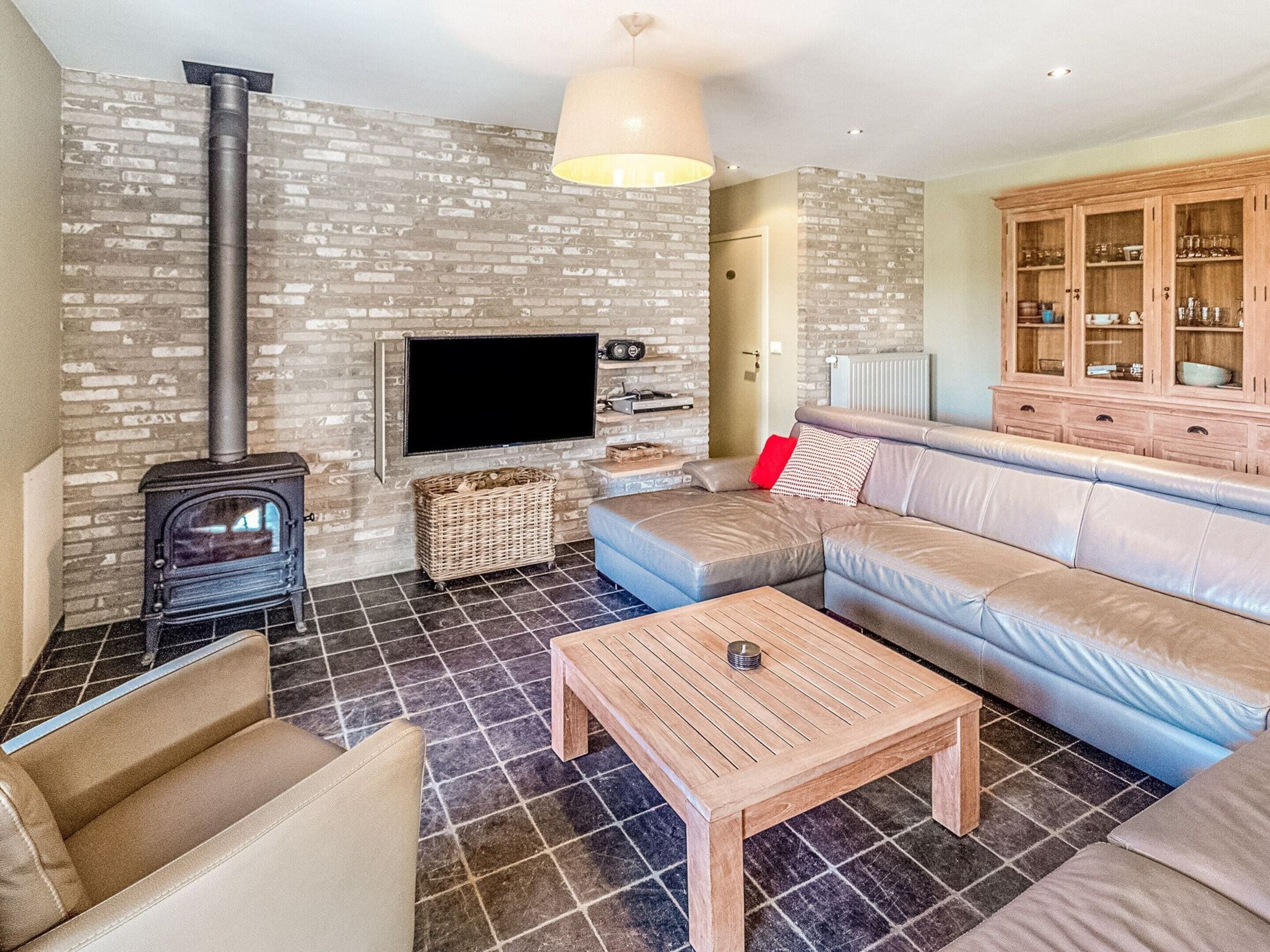 A living room with a fireplace, a sofa, a television, and a cabinet.