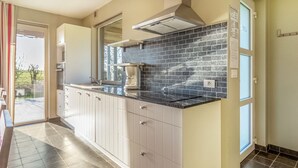 A modern kitchen with dark tiled backsplash, white cabinets, and a black countertop. - Ideal Holiday Home in Gijverinkhove With Terrace, Garden (Alveringem)