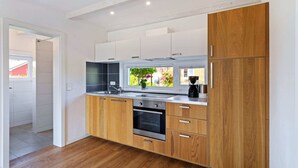 A modern kitchen with wooden cabinets, a stainless steel sink, and an oven. - Charming Holiday Home in Zierow Near Seabeach (Zierow)