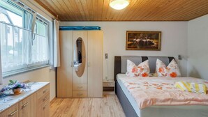 Un dormitorio con techo de madera, cama con ropa de cama floral, armario y un cuadro de flamencos.