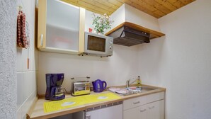 Una cocina compacta equipada con microondas, tostadora, cafetera y lavaplatos.
