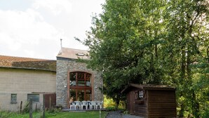 A rustic building with a stone facade, a wooden door, and a small wooden structure to the right. - Renovated Farmhouse From 1832 With Beautiful View of Winter Sports Area (Vielsalm)