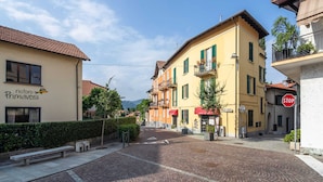 A cobblestone street lined with colorful buildings, including a restaurant named "ristoro Primavera." - Modern Apartment in Meina Near the Lake (Meina)