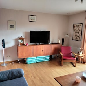 A living room with a television, a red chair, a sofa, and a wooden cabinet. - Lovely Holiday Home in Stipshausen With Terrace (Stipshausen)