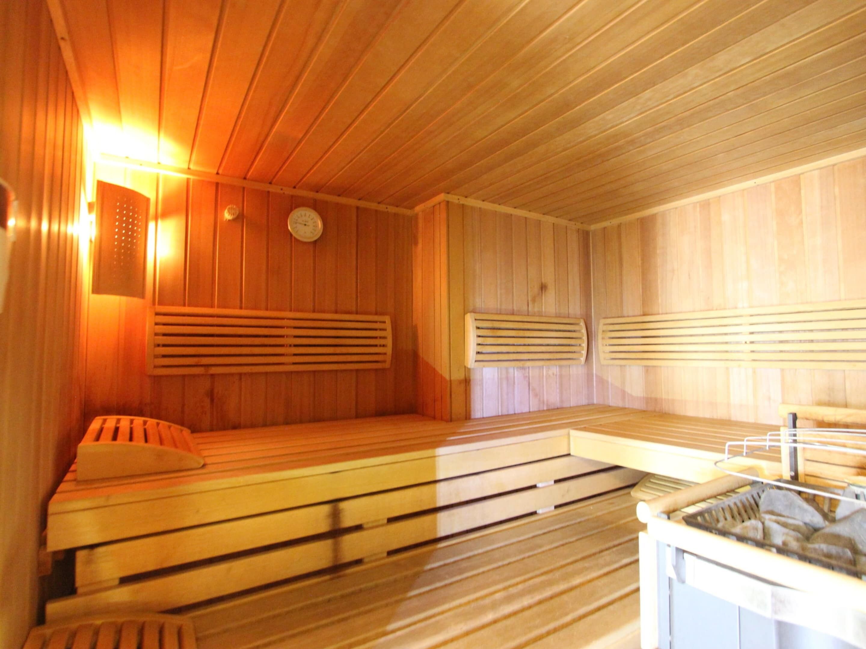 Un sauna avec des bancs en bois, un radiateur fixé au mur et une horloge.