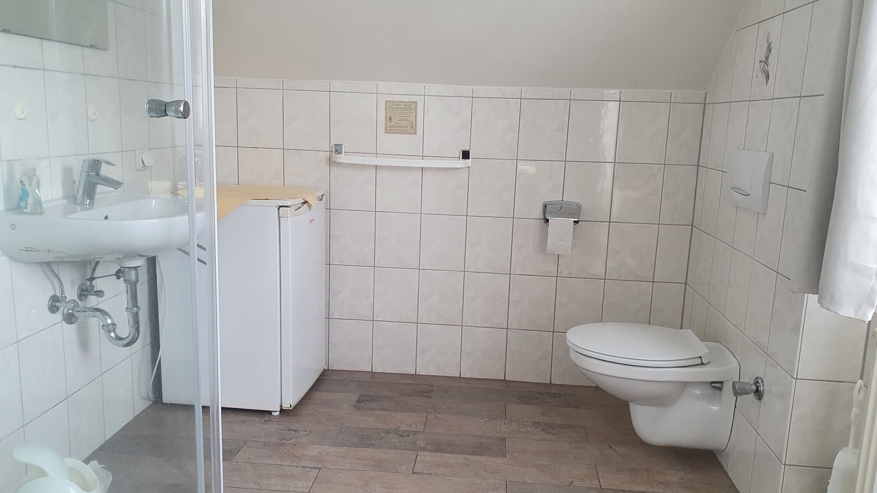 A small bathroom with a toilet, sink, and shower.