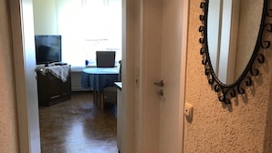 Ein Flur, der zu einem Zimmer mit Fernseher, Tisch und Stuhl führt.