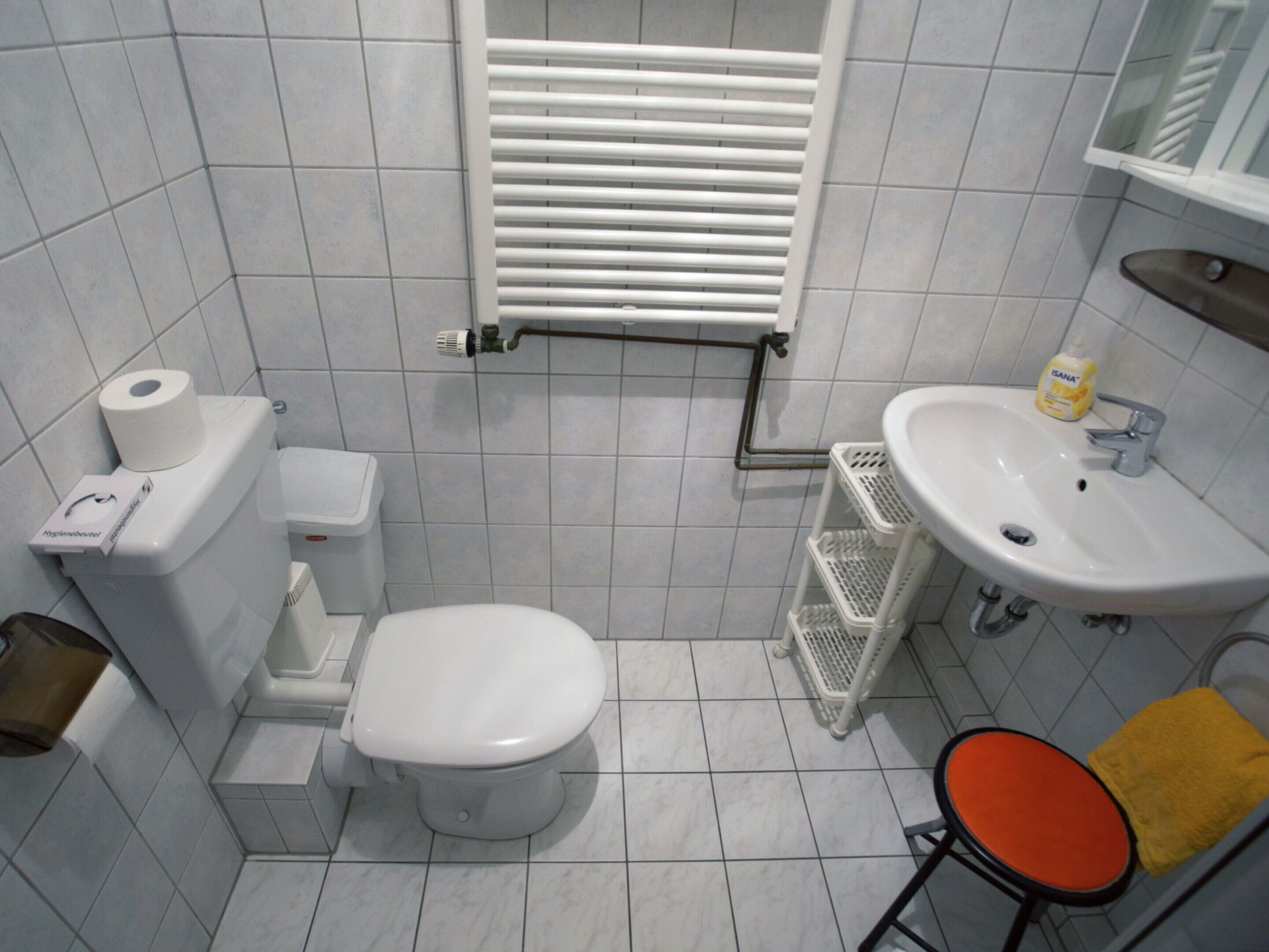 A small bathroom with a toilet, sink, and a towel rack.