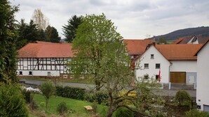 Ein traditionelles Fachwerkhäuschen mit rotem Ziegeldach, umgeben von einem gepflegten Garten und einer klaren Straße im Hintergrund.