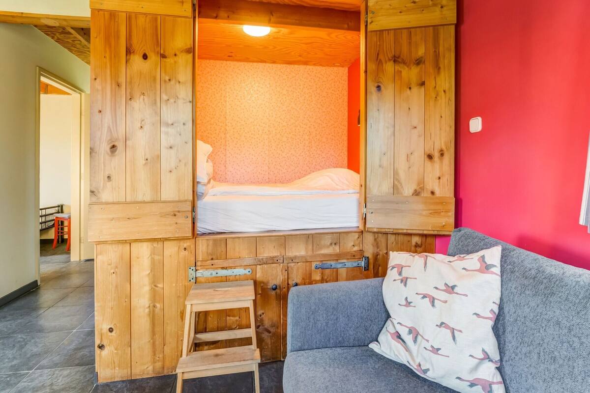 A room with a bed, a gray sofa, and a wooden ladder.